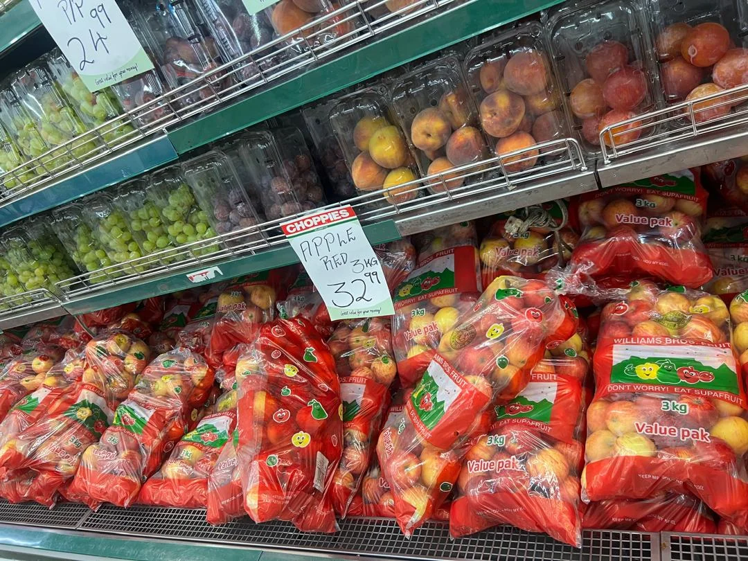 Apples and peaches displayed in a supermarket produce aisle